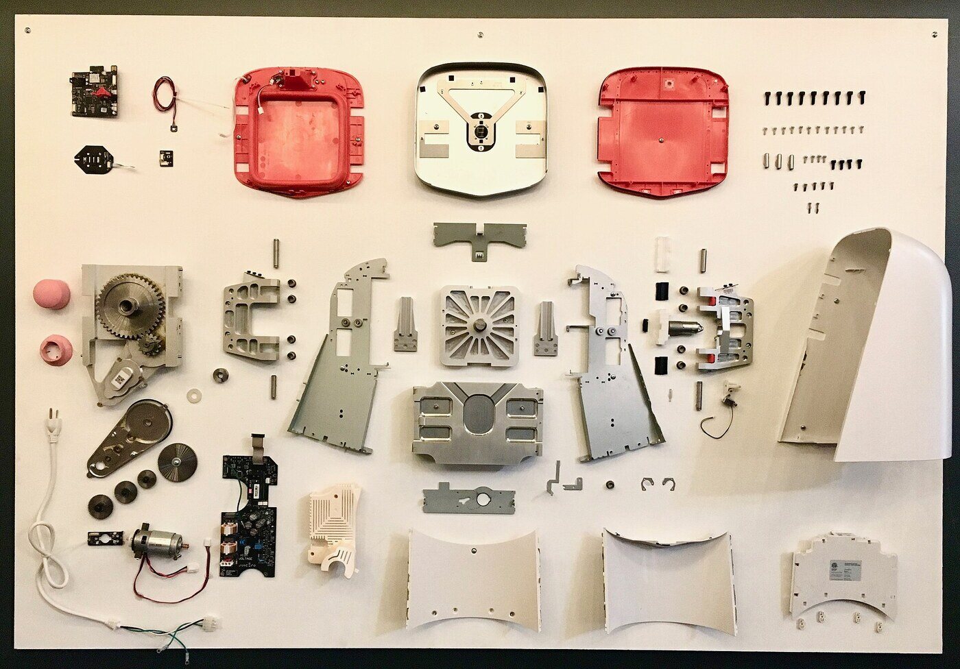 A Juicero Press taken apart and mounted as an exhibit in 2018, a year after the company closed: the aluminium frame, the drive train and the plates that pressed a bag of cut fruit.